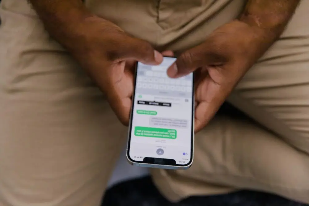 Close-up of a man texting on a smartphone held between his knees