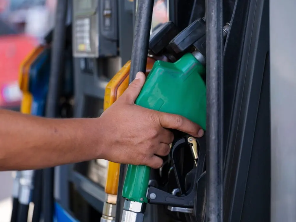 Hand holding a fuel nozzle at a gas pump, where September retail sales got a big lift