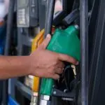 Hand holding a fuel nozzle at a gas pump, where September retail sales got a big lift