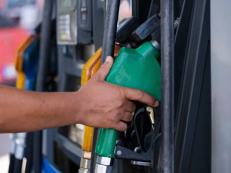 Hand holding a fuel nozzle at a gas pump, where September retail sales got a big lift