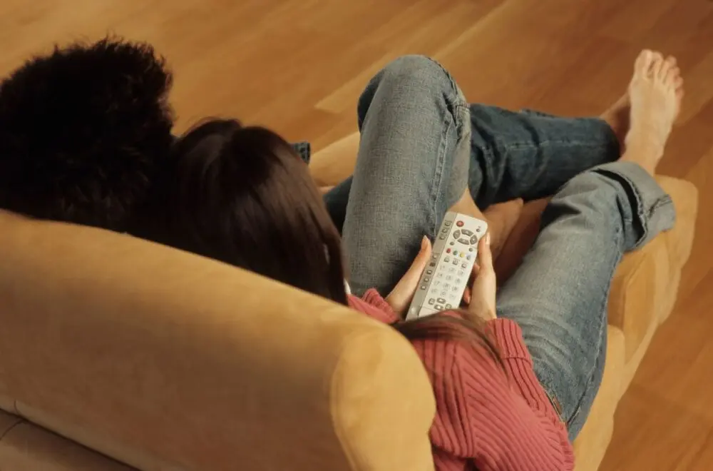 Couple relaxing on a couch with a remote, watching streaming at home