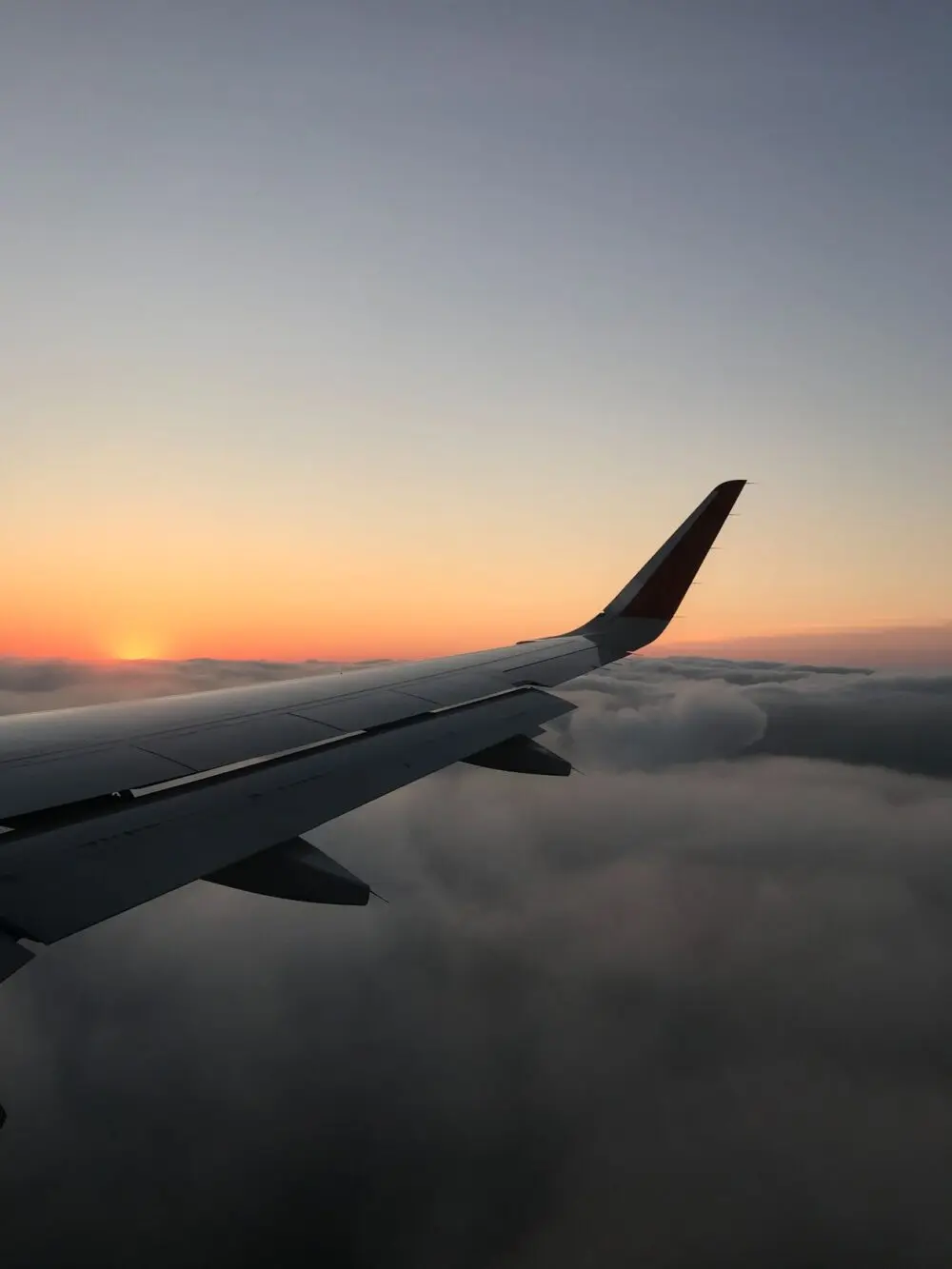 Airplane wing at sunset above dark clouds, illustrating United Airlines earnings and fuel costs