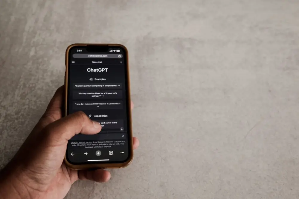 Hand using a smartphone ChatGPT conversation to review ChatGPT ads settings