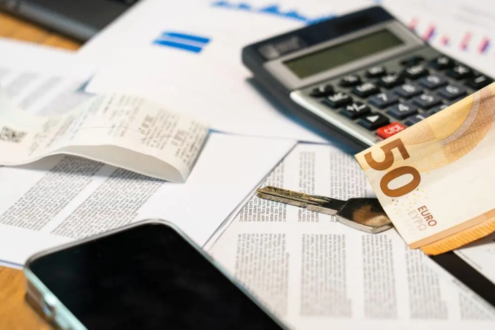 Calculator, phone and papers on a desk for reviewing a household budget