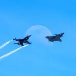 Two military fighter jets in a clear sky, a Lockheed Martin earnings theme