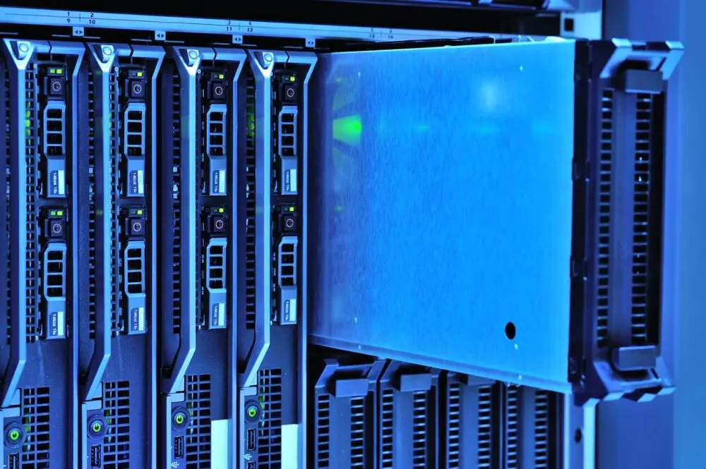 Rack-mounted servers lit in blue with one unit pulled partway out, stock image of data center hardware