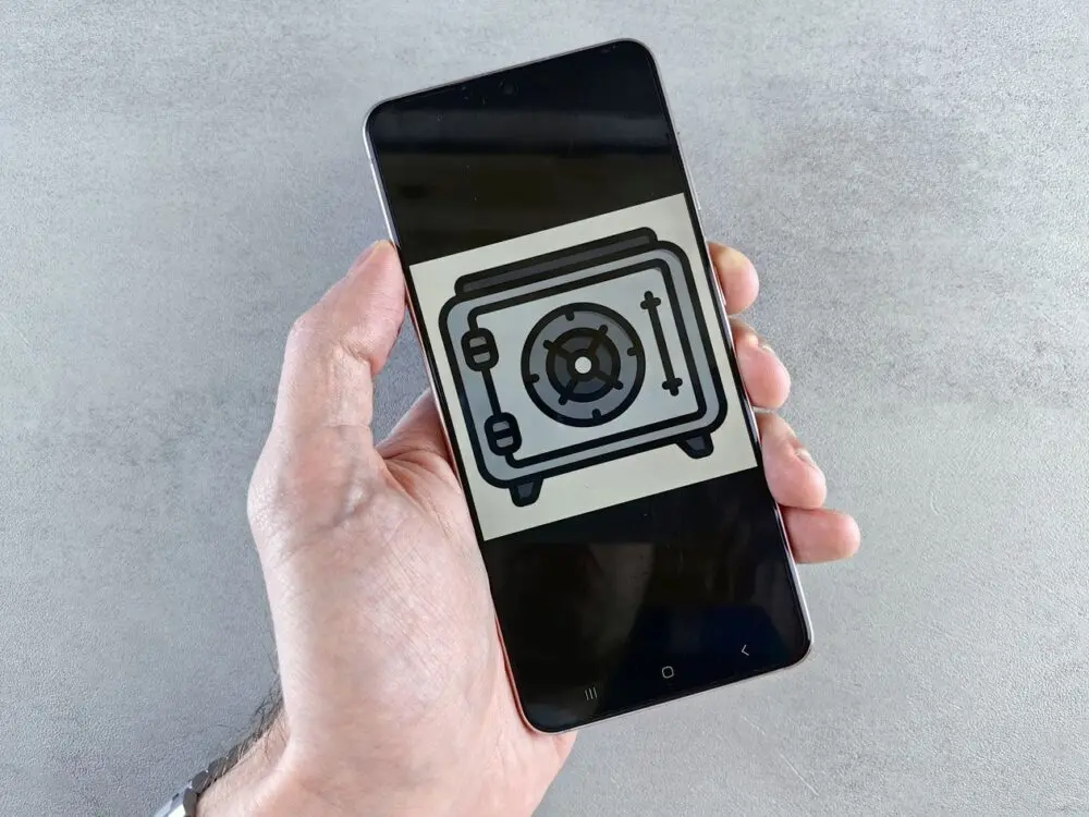 Hand holding a smartphone showing a safe icon, a symbol of secure sign-in