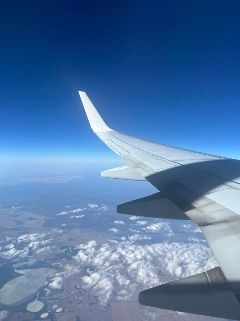 Airplane wing and winglet above clouds against a deep blue sky