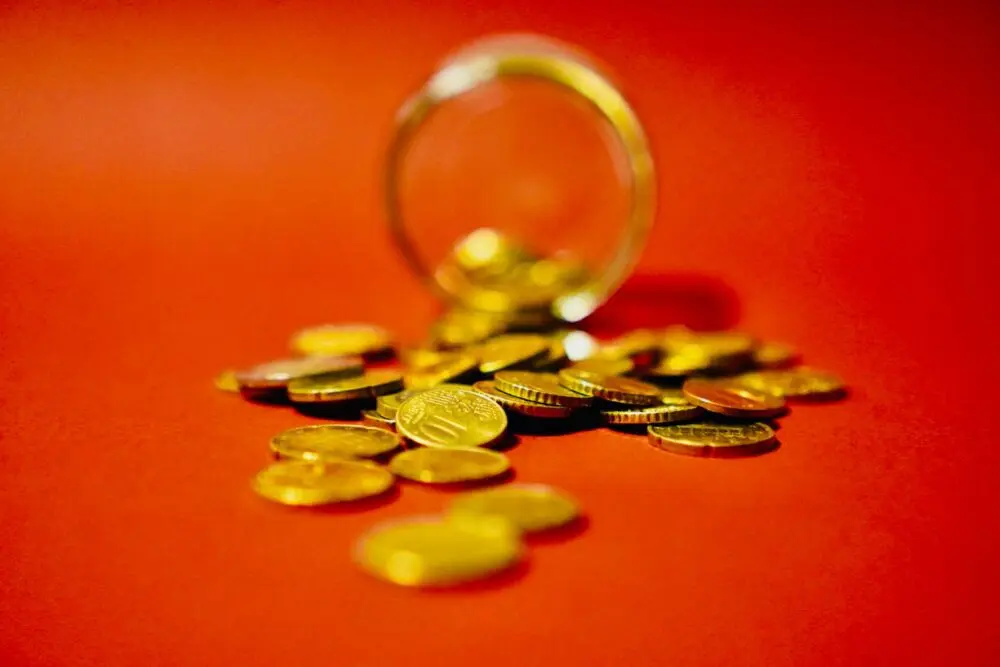 Coins spilling from a glass jar on an orange background, representing what savings rates pay