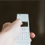 Hand holding a remote in front of a TV, like the new Apple TV 4K