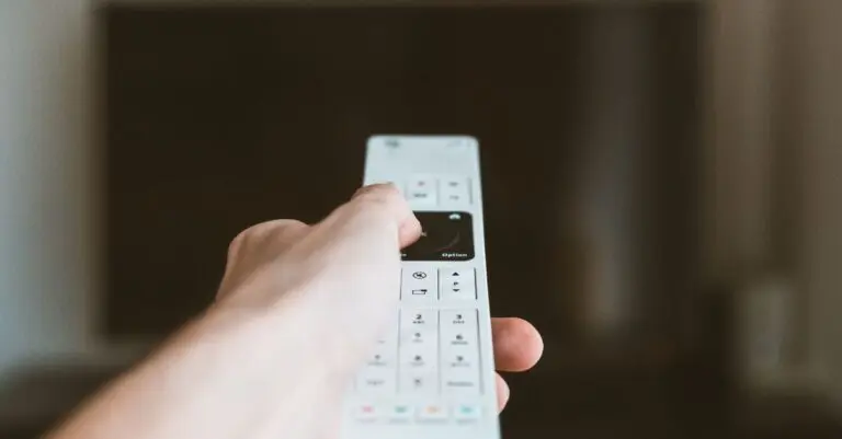 Hand holding a remote in front of a TV, like the new Apple TV 4K