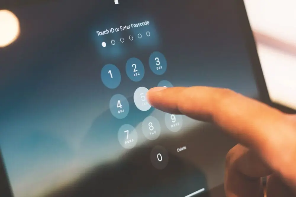 Finger entering a passcode on a touchscreen keypad before you set up passkeys