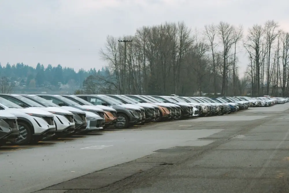 Long row of parked cars on an overcast day, used-car inventory in the Copart ACV acquisition