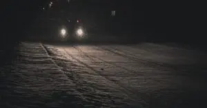 Car headlights on a dark road after daylight saving time ends
