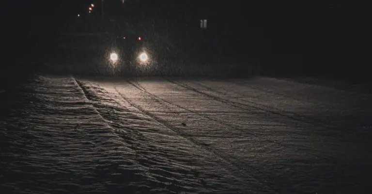 Car headlights on a dark road after daylight saving time ends