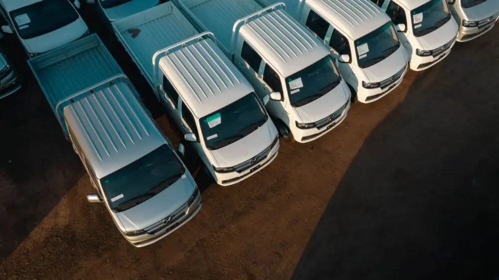 Aerial view of pickup trucks and vans waiting on a lot, showing the inventory GM earnings will reflect