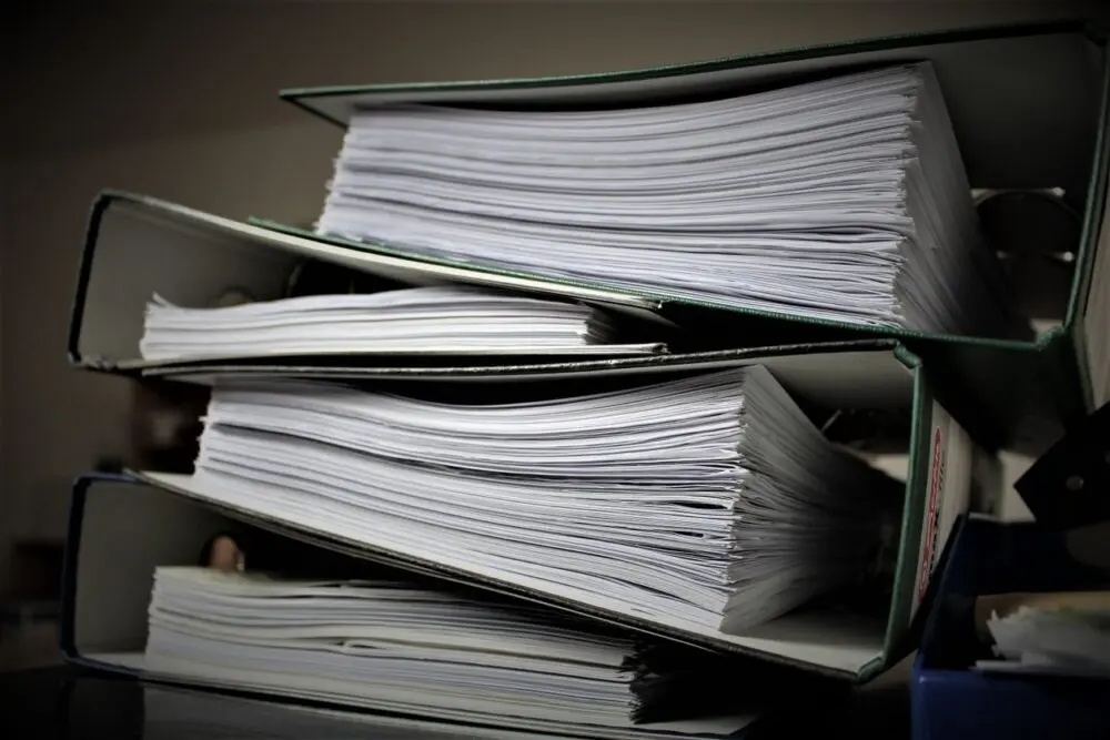 Shelves of binders holding contracts to review before AI liability insurance renewal