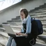 Student using a laptop on outdoor stairs to fill out the FAFSA