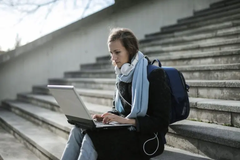 Student using a laptop on outdoor stairs to fill out the FAFSA