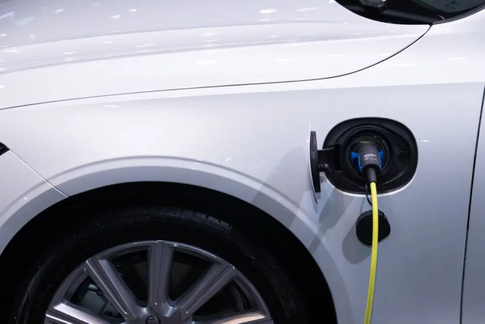 Close-up of a white electric car with a charging cable plugged into its port