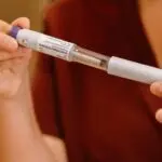 Hands holding a medication injection pen, illustrating the Eli Lilly Q3 earnings