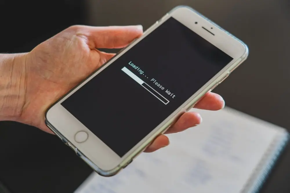 Hand holding a phone with a progress bar while it tries to back up your phone