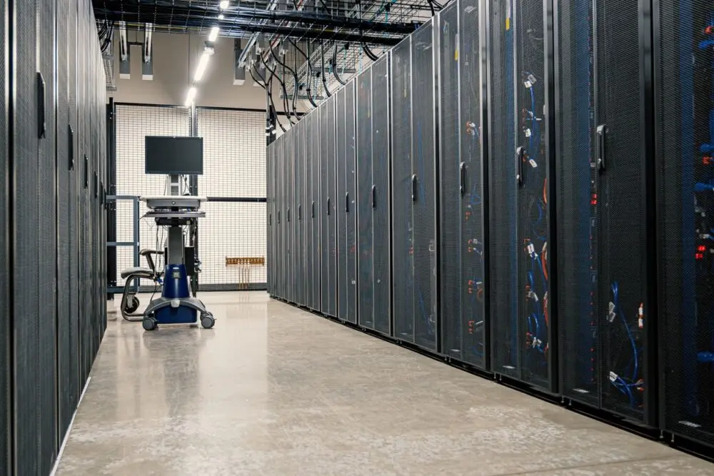A long aisle of server cabinets in a data hall, a symbol of AI spending in the Meta earnings debate