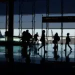 Silhouettes of travelers in an airport terminal, a scene where REAL ID requirements apply