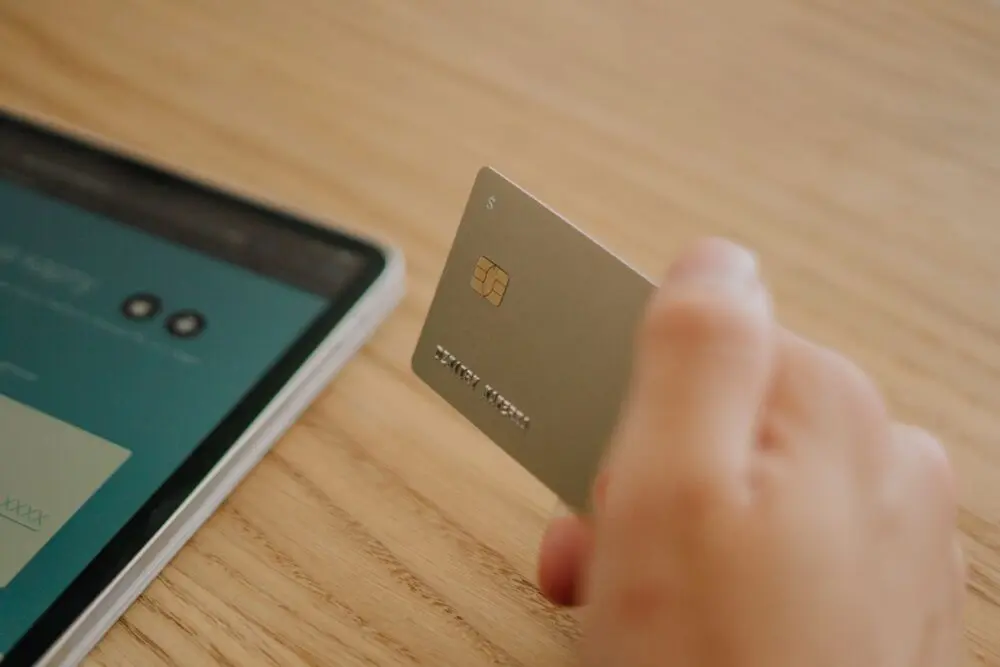 Person holding a bank card in front of a laptop to manage a credit freeze online