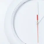 White wall clock with a red second hand, a reminder that daylight saving time ends November 1
