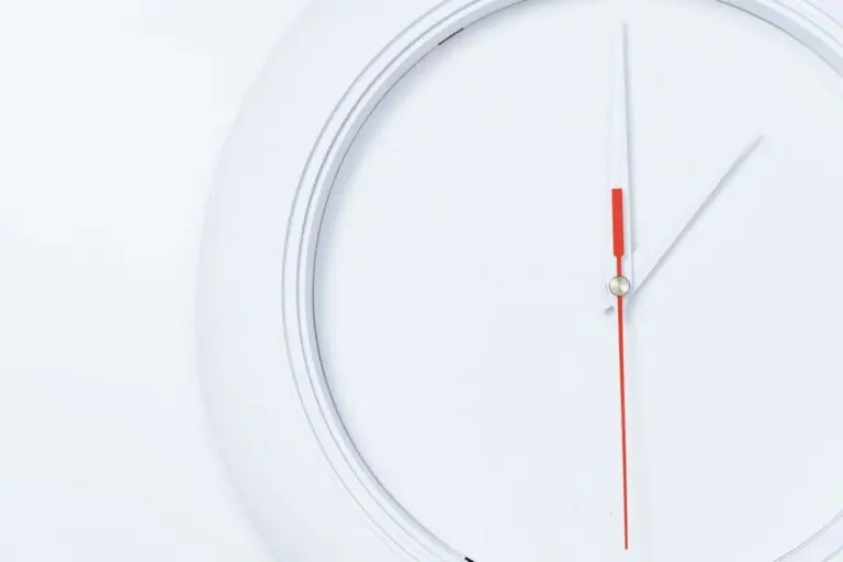White wall clock with a red second hand, a reminder that daylight saving time ends November 1