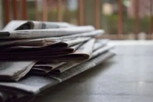 Stack of folded newspapers on a table, illustrating the Anthropic copyright lawsuit by news publishers