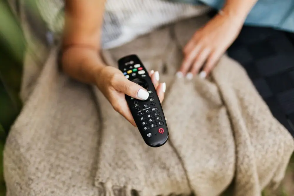 Person on a couch holding a TV remote while checking privacy settings