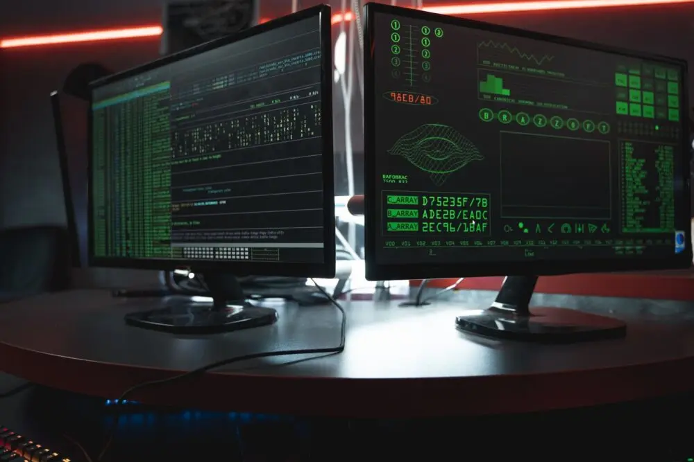 Dual monitors with green code in a dark room, a ConnectWise attack security theme