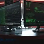Dual monitors with green code in a dark room, a ConnectWise attack security theme