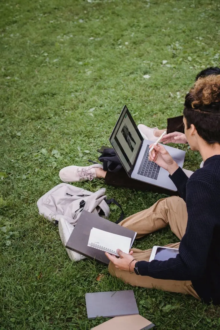 Two students study on a laptop outdoors, like many SAVE plan borrowers weighing repayment options