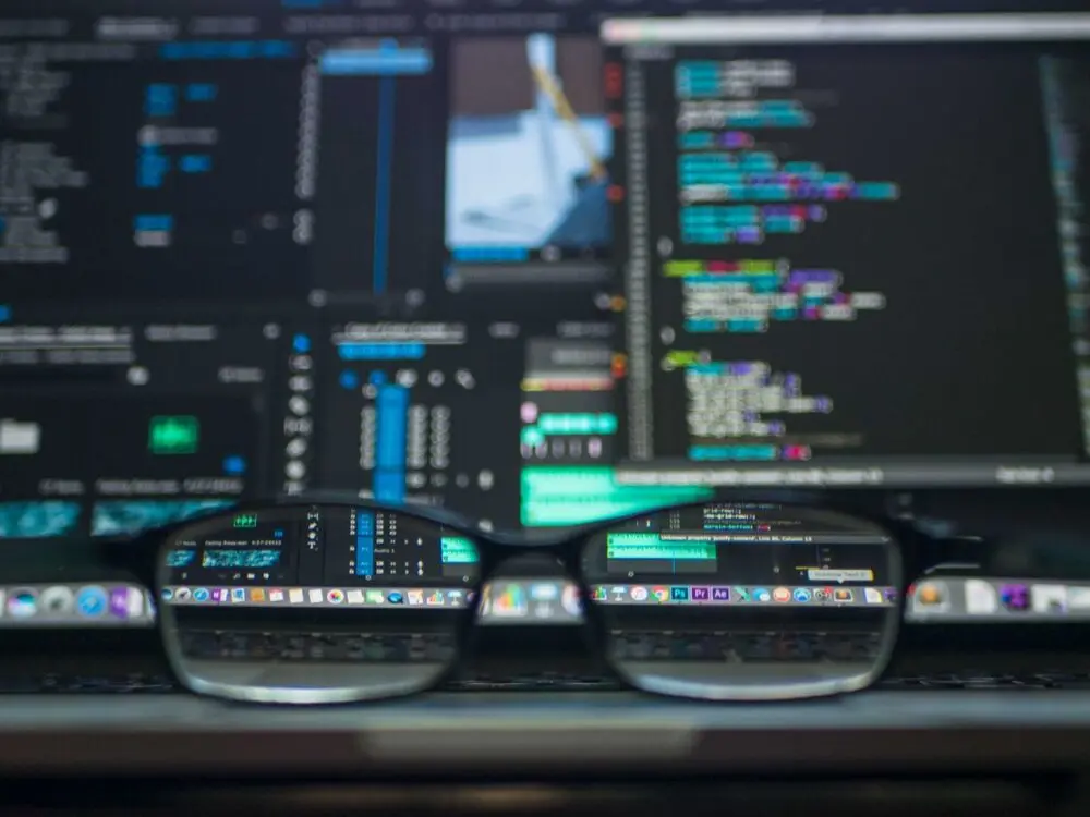 Glasses resting in front of computer monitors displaying code