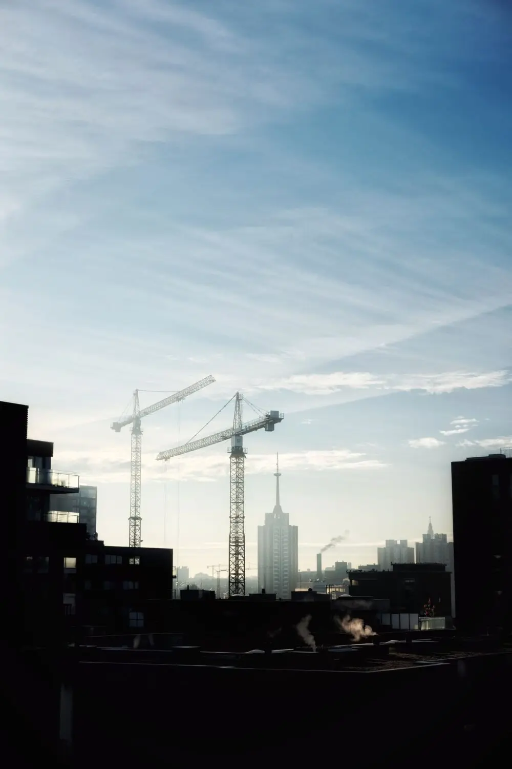 Construction cranes silhouetted against a morning sky, illustrating Q3 GDP investment and housing