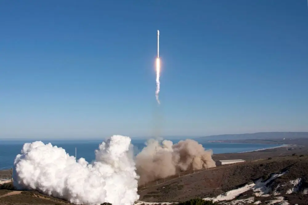 A rocket launching over the ocean with a plume of smoke below