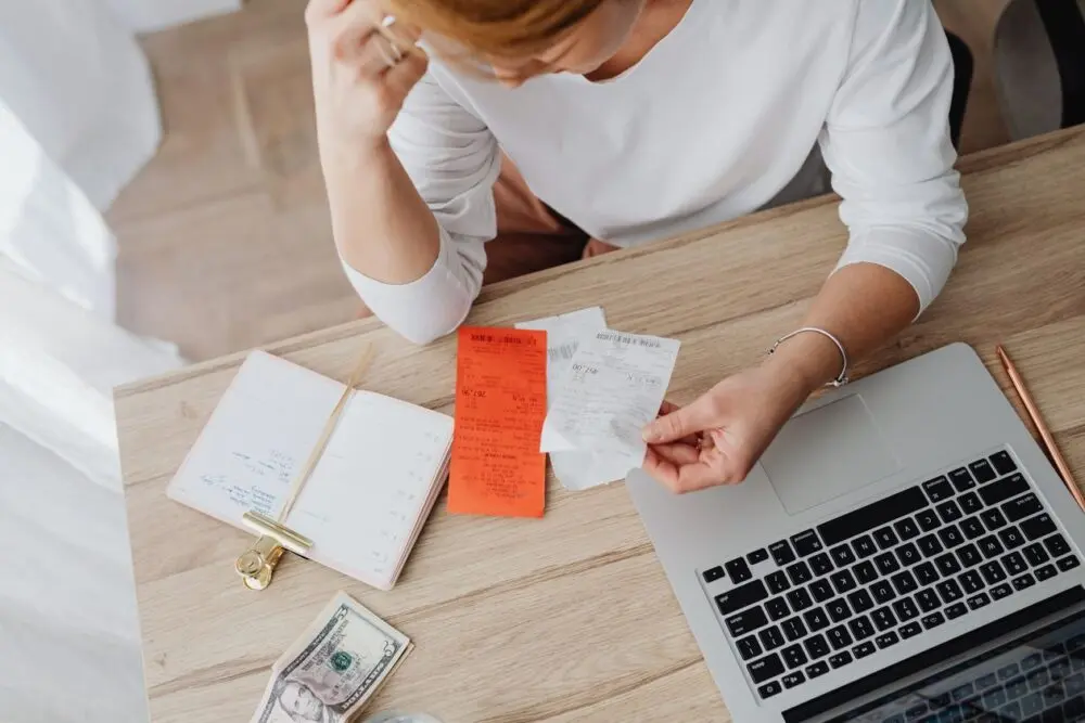 Woman reviewing receipts and planning a budget on a laptop, weighing a SAVE plan final notice