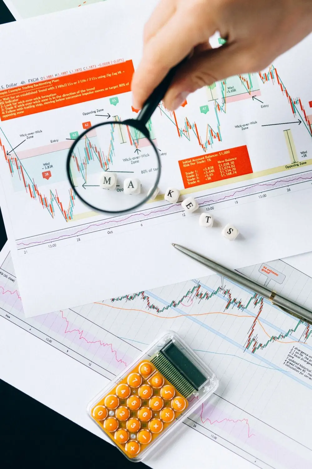 Magnifying glass held over market charts, a generic image for reading the data