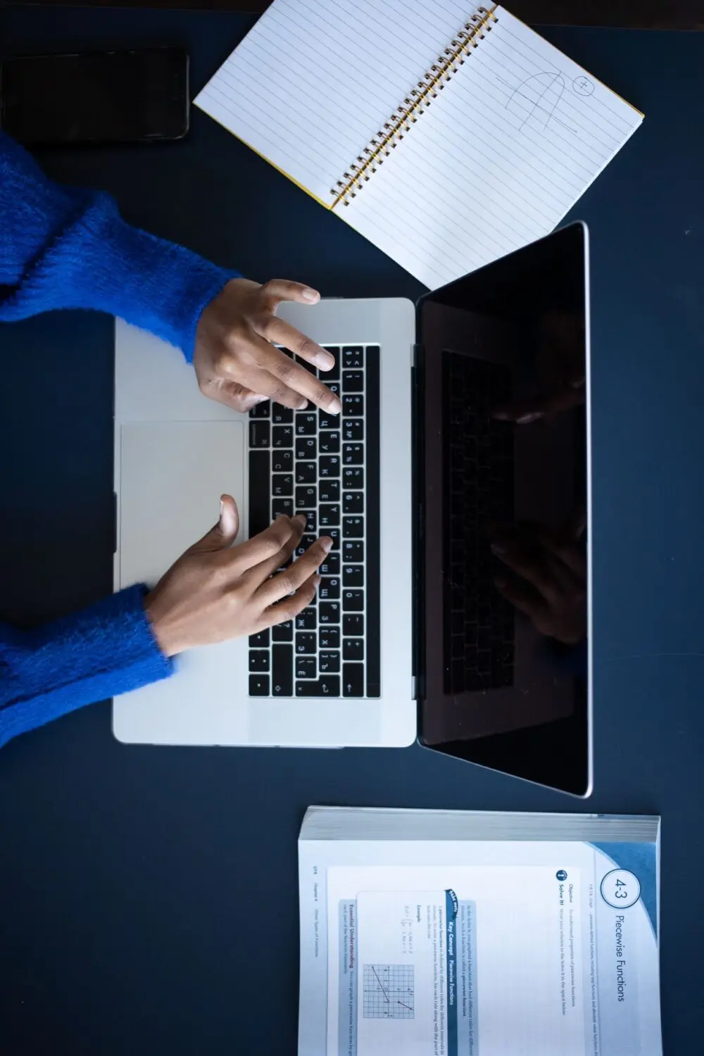 Overhead view of hands on a laptop keyboard, checking the answers to AI prompts
