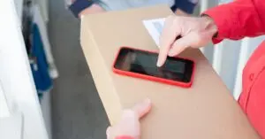Smartphone on a carton box showing how a fake delivery text can look