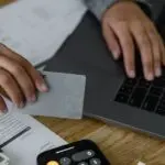 Person holding a credit card at a laptop to make a balance transfer