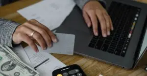 Person holding a credit card at a laptop to make a balance transfer