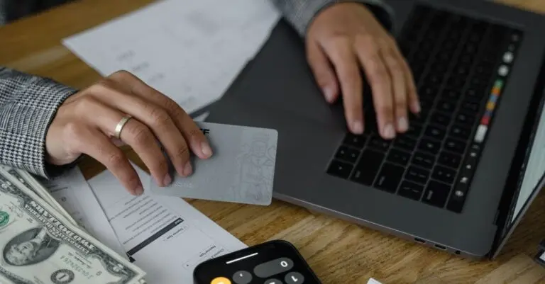 Person holding a credit card at a laptop to make a balance transfer