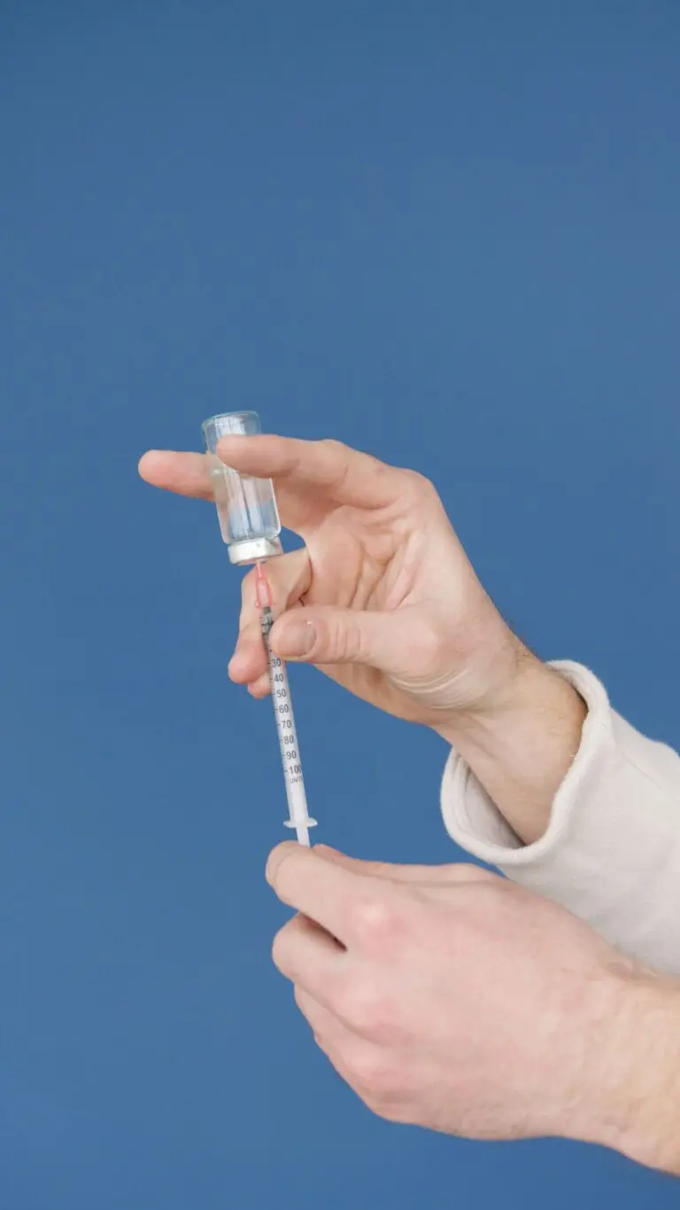 Hands filling a syringe with vaccine from a vial, illustrating the flu shot
