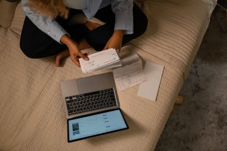 Overhead view of a woman holding a check and a laptop while searching for unclaimed property
