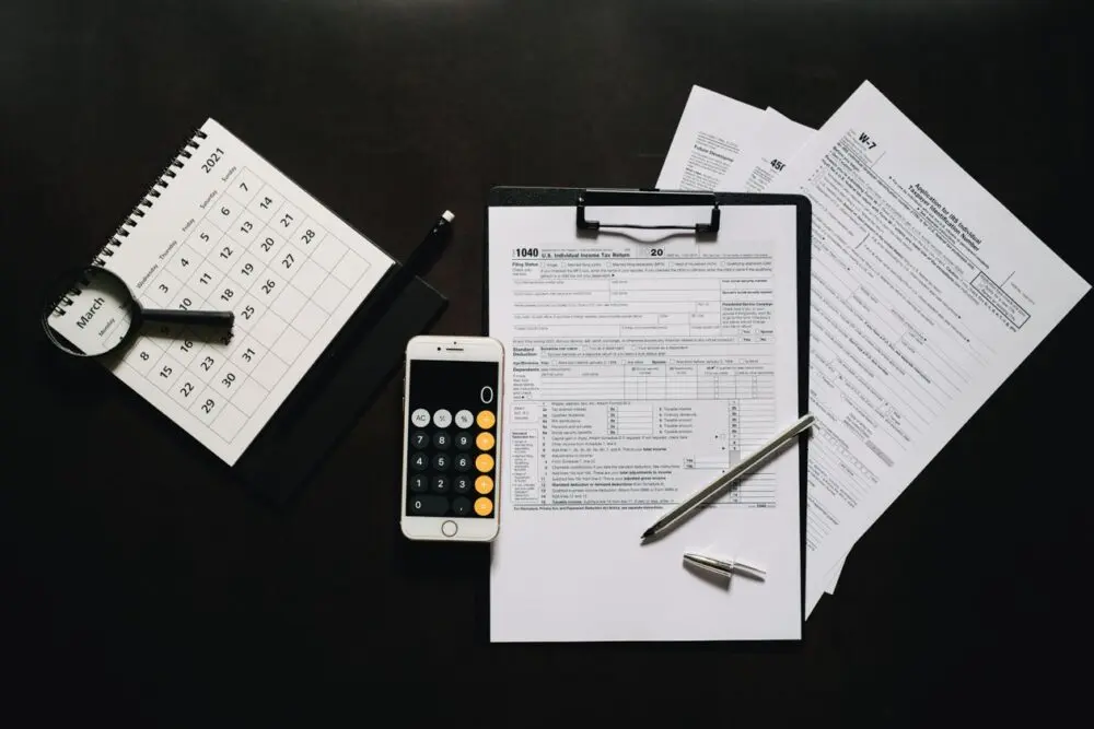 Flat lay of tax paperwork, a clipboard and a phone for retirement limit planning