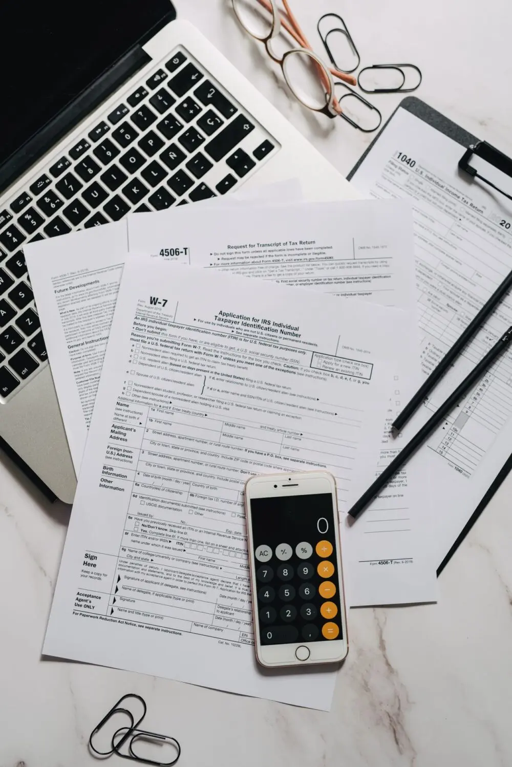 Stack of tax and investment forms on a desk, like the tender-offer paperwork behind private credit redemptions
